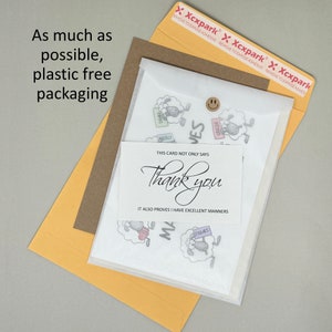 May include: A white card with black text that reads "This card not only says Thank you, it also proves I have excellent manners". The card is surrounded by small images of sheep holding signs that say "Thanks", "Merci", "Grazie", and "Danke".