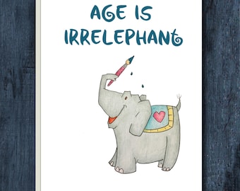 May include: A white greeting card featuring a cartoon gray elephant holding a paintbrush with its trunk. The elephant wears a blue blanket with a pink heart. The text at the top reads AGE IS IRRELEPHANT in blue, stylized, rounded lettering.