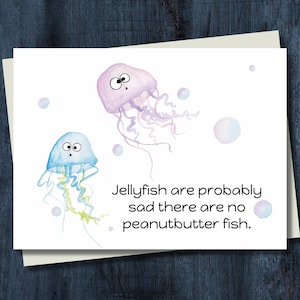 May include: A white greeting card featuring watercolor illustrations of two jellyfish and bubbles. The text reads, "Jellyfish are probably sad there are no peanutbutter fish."