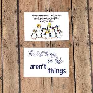 May include: Two white cards with blue text. The top card features a group of cartoon penguins wearing hats and the text "Always remember that you are absolutely unique, just like everyone else." The bottom card features the text "The best things in life aren't things."