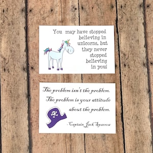 May include: Two inspirational quotes on white cards. The first card features a cartoon unicorn with the text "You may have stopped believing in unicorns, but they never stopped believing in you!" The second card features a cartoon pirate hat with the text "The problem isn't the problem. The problem is your attitude about the problem. - Captain Jack Sparrow"