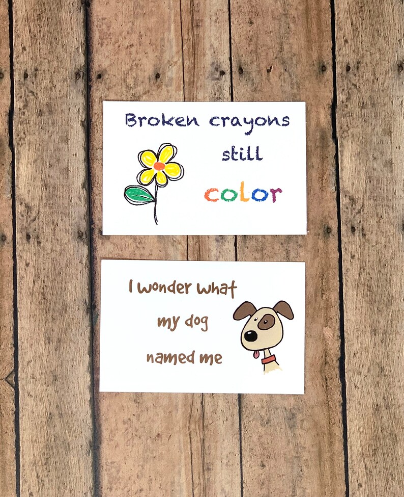 May include: Two cards with hand-drawn illustrations and text. The first card features a yellow flower with a green stem and leaves. The text reads "Broken crayons still color". The second card features a brown dog with a red collar and the text "I wonder what my dog named me".