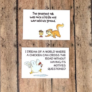 May include: Two illustrated cards with inspirational quotes. The first card features a cartoon acorn and squirrel with the text "The greatest oak was once a little nut who held his ground." The second card features a cartoon chicken crossing the road with the text "I dream of a world where a chicken can cross the road without having its motives questioned."