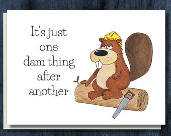 May include: A greeting card with a cartoon beaver wearing a yellow hard hat, sitting on a log with a saw. The card reads "It's just one dam thing after another."
