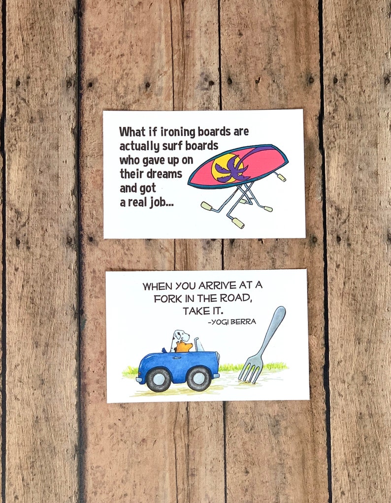 K&ouml;nnte beinhalten: Zwei illustrierte Karten mit humorvollen Spr&uuml;chen. Die obere Karte zeigt ein rosa und gelbes B&uuml;gelbrett mit einem Palmenbaum darauf und den Text "What if ironing boards are actually surf boards who gave up on their dreams and got a real job..." Die untere Karte zeigt ein blaues Auto mit einem Hund und einem B&auml;ren darin, das auf eine gro&szlig;e Gabel in der Stra&szlig;e zuf&auml;hrt. Der Text lautet "When you arrive at a fork in the road, take it. -Yogi Berra"