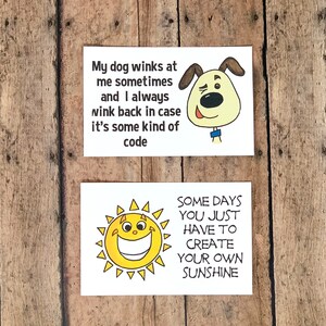 K&ouml;nnte beinhalten: Zwei wei&szlig;e Karten mit schwarzem Text und Illustrationen. Die obere Karte zeigt einen winkenden Cartoon-Hund und den Text "Mein Hund zwinkert mir manchmal zu und ich zwinkere immer zur&uuml;ck, falls es sich um eine Art Code handelt". Die untere Karte zeigt eine Cartoon-Sonne mit einem breiten L&auml;cheln und den Text "Manchmal muss man einfach seinen eigenen Sonnenschein schaffen".
