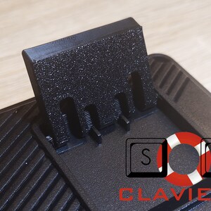 May include: Black keyboard wrist rest with a textured surface and a black plastic stand with three slots. The stand is attached to the wrist rest and can be raised to elevate the keyboard.
