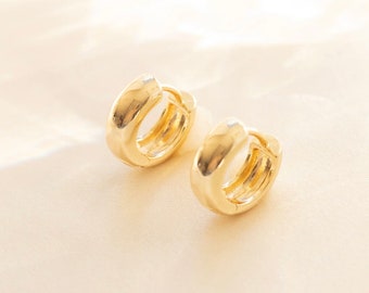 May include: A pair of gold hoop earrings. The earrings are thick and have a rounded shape.