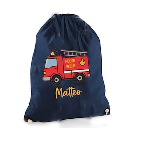 Könnte beinhalten: Dunkelblauer Turnbeutel mit rotem Feuerwehrauto-Design und dem Schriftzug "FEUER WEHR". Der Name "Matteo" ist in Gelb gedruckt. Der Beutel hat einen weißen Kordelzugverschluss.