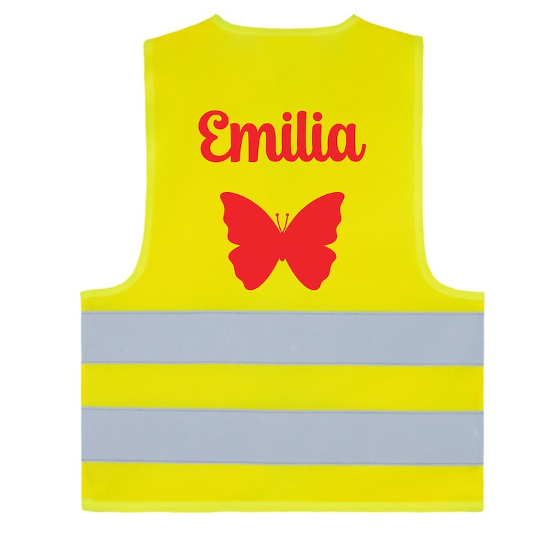May include: A bright yellow safety vest with reflective stripes. The vest features the name "Emilia" in red script above a red butterfly graphic. The vest is designed for visibility and safety.