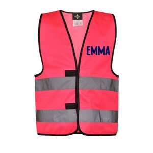 May include: A bright pink safety vest with black trim and reflective silver stripes. The word "EMMA" is printed in navy blue on the upper right chest area. The vest has a V-neck and two black velcro closures.