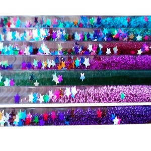 Könnte beinhalten: Ein Satz von acht durchsichtigen Plastikröhrchen, gefüllt mit buntem Glitzer und Sternen. Die Röhrchen sind in einer Reihe angeordnet, wobei das unterste Röhrchen das größte und das oberste Röhrchen das kleinste ist.