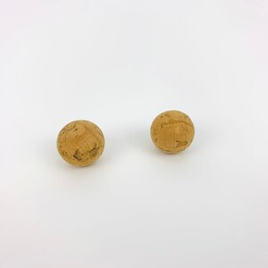 May include: Two brown cork balls on a white background.