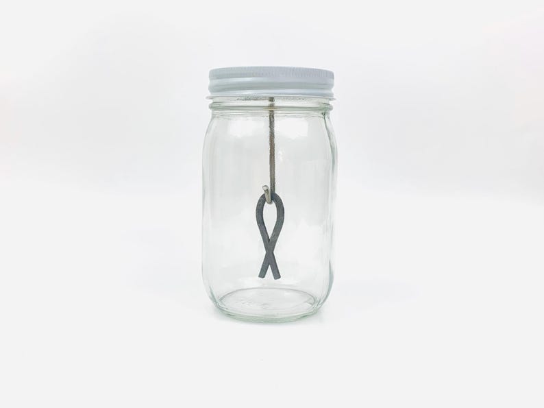 May include: A clear glass jar with a white lid and a metal figure eight hanging inside.