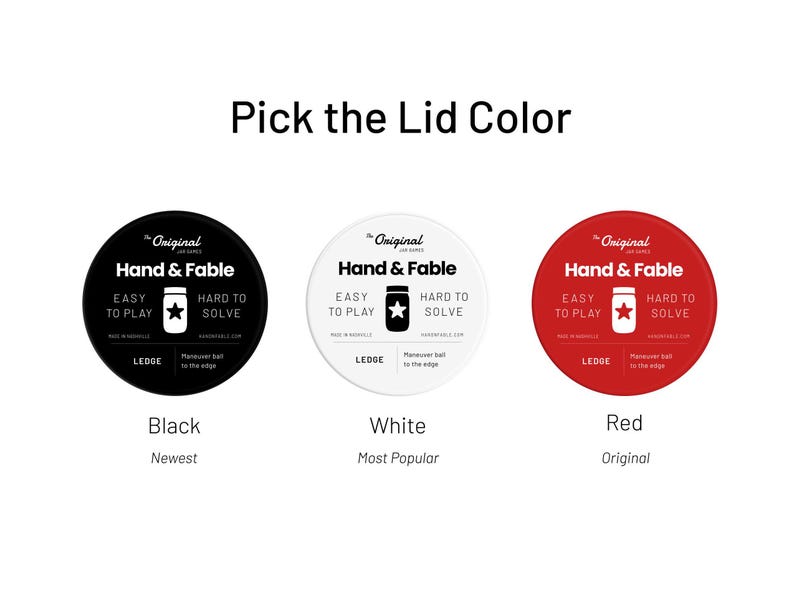 May include: Three round labels with the text "The Original Jar Games Hand & Fable" in black text on a white background. The labels are black, white, and red. The text "Black", "White", and "Red" is below each label. The text "Newest", "Most Popular", and "Original" is below the color names.