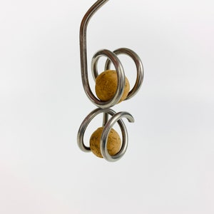 May include: A silver metal wine bottle stopper with two cork balls. The stopper is designed with a spiral shape.