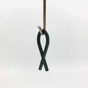 May include: A black rubber fish-shaped hook hanging from a silver hook.