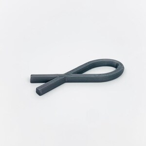 May include: A gray plastic ribbon shaped like a fish.