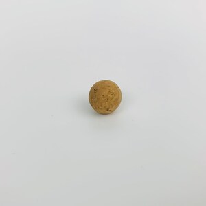 May include: A round, brown cork stopper.