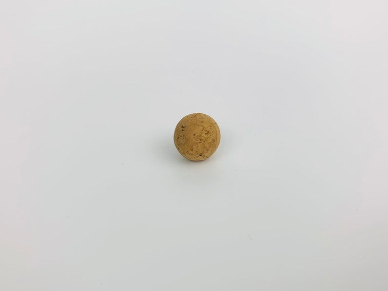May include: A round, brown cork stopper.