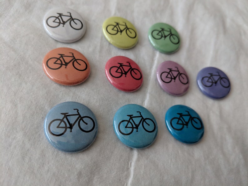 Puede incluir: Una colecci&oacute;n de botones redondos y coloridos con un dise&ntilde;o de bicicleta negra. Los botones est&aacute;n disponibles en varios tonos pastel, incluyendo blanco, amarillo, verde, naranja, rojo, rosa, morado, azul claro y turquesa. Ideales para personalizar ropa o accesorios.