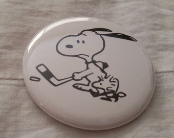 Snoopy y Woodstock jugando hockey sobre hielo, botón o imán de 2,25 pulgadas