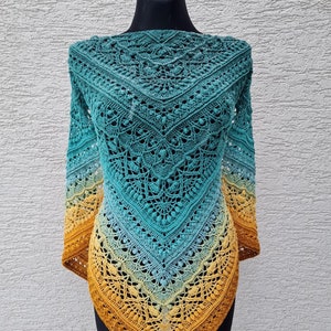 May include: A crocheted shawl with a gradient of teal, blue, and yellow colors. The shawl is made with a delicate lace pattern and has a fringed edge.