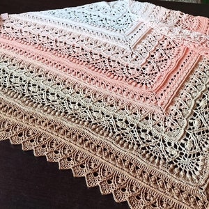 May include: A crocheted shawl with a gradient of colors from white to pink to brown. The shawl has a delicate lace pattern and a scalloped edge.