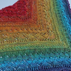 May include: A rainbow crochet shawl with a lacy pattern and a scalloped edge.