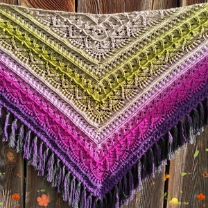 May include: A crocheted shawl with a gradient of green, purple, and pink colors. The shawl has a fringe border and is made with a delicate stitch pattern.