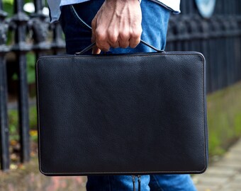 May include: A black leather laptop sleeve with a zipper closure and brown stitching detail.