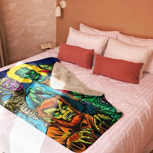Puede incluir: Una manta de forro polar colorida con un estampado gr&aacute;fico de varios monstruos, incluyendo un hombre lobo, una momia y un monstruo de Frankenstein. La manta est&aacute; sobre una cama con almohadas.