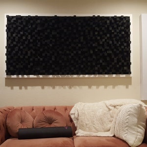 Puede incluir: Una sala de estar con un sofá y una pared cubierta con paneles acústicos de espuma negra. Los paneles están enmarcados en blanco y están dispuestos en una cuadrícula. Hay dos paneles blancos a cada lado de los paneles de espuma.