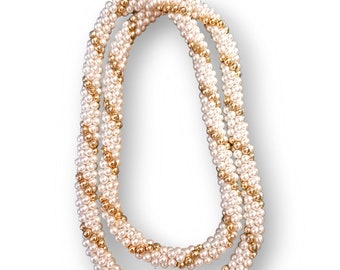 May include: A white and gold beaded necklace with a twisted design.