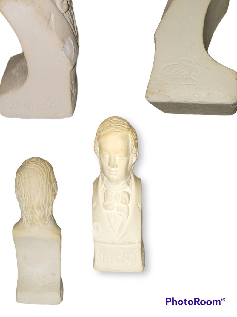 May include: White plaster bust of a man with short hair and a bow tie. The bust is on a base with the word "SCHUMANN" inscribed on it.