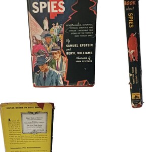 May include: A vintage paperback book titled "The Real Book About Spies" with a black and white illustration of spies on the cover. The book is part of a series called "An Increasingly Popular Series" and has a red spine with the title "The Real Book About Spies" in white text.