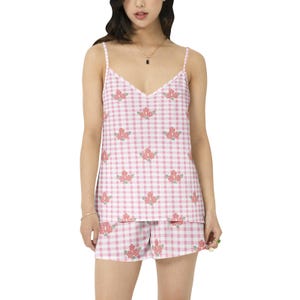 Puede incluir: Un conjunto de pijama de cuadros vichy rosa y blanco con estampado floral. La parte superior es un top sin mangas con cuello en V. Los pantalones cortos son de corte holgado.