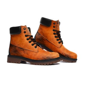 Puede incluir: Un par de botas hasta el tobillo con un acabado jaspeado en naranja y marrón y cuellos acolchados negros. Las botas incluyen cordones negros, ojales metálicos negros y una suela de goma gruesa de color marrón oscuro con tacos.