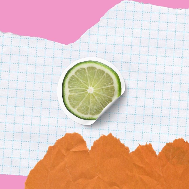 May include: A close-up of a lime wedge on a white gridded background with a torn orange paper background.