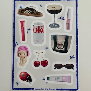 May include: A sheet of stickers featuring various images, including a leopard print shoe, a cocktail, a can of Diet Coke, a Trader Joe's bag, a cherry, sunglasses, a ladybug, and a tube of lip gloss. The text "everafter the brand" is printed at the bottom of the sheet.