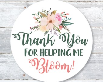 May include: A circular white sticker featuring a floral design and the text "Thank You For Helping Me Bloom!" in green and coral lettering. The floral arrangement includes pink, peach, and green watercolor flowers.