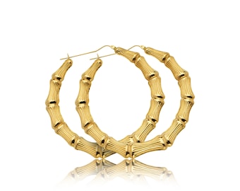 May include: A pair of large gold hoop earrings with a bamboo-like design. The earrings are made of metal and have a shiny finish.