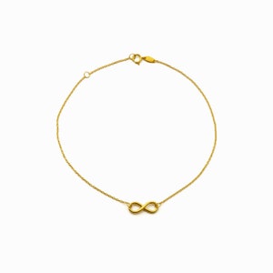 May include: A gold infinity symbol charm bracelet with a delicate chain.