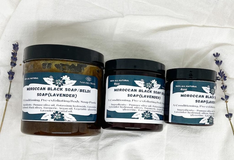 K&ouml;nnte beinhalten: Drei Gl&auml;ser mit marokkanischer schwarzer Seife mit Lavendel. Die Gl&auml;ser sind mit dem Produktnamen, den Zutaten und der Gr&ouml;&szlig;e beschriftet. Die Gl&auml;ser stehen auf einer wei&szlig;en Oberfl&auml;che mit Lavendelbl&uuml;ten.