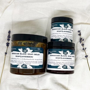 K&ouml;nnte beinhalten: Drei Gl&auml;ser mit marokkanischer schwarzer Seife mit Lavendel-&Ouml;l. Die Gl&auml;ser sind mit "Marokkanische schwarze Seife/Beldi Seife (Lavendel)" beschriftet und haben ein Fassungsverm&ouml;gen von 4 oz, 8 oz und 8 oz. Die Gl&auml;ser stehen auf einem wei&szlig;en Stoffuntergrund mit Lavendelbl&uuml;ten.