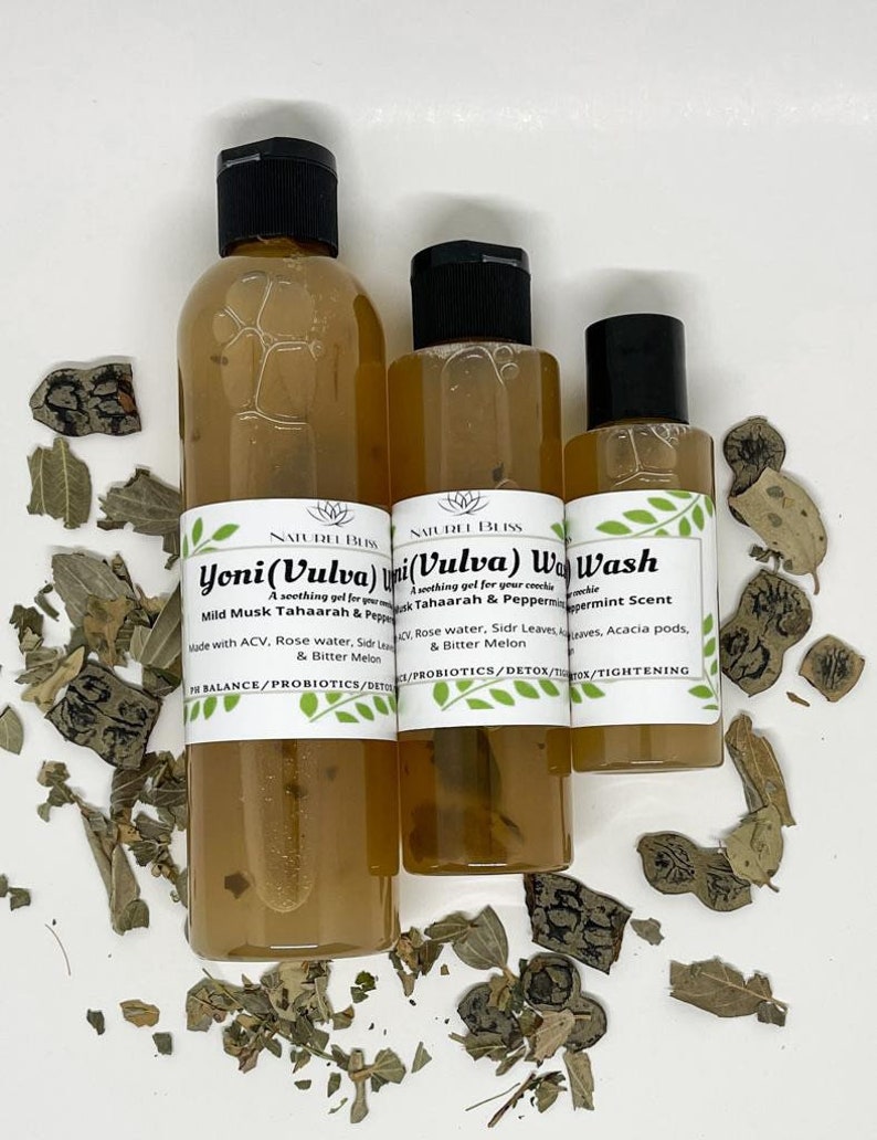 May include: Three bottles of clear liquid with white labels. The labels have the text "Yoni (Vulva) Wash" and "Mild Musk Tahaarah & Peppermint Scent". The bottles are on a white surface with dried leaves.