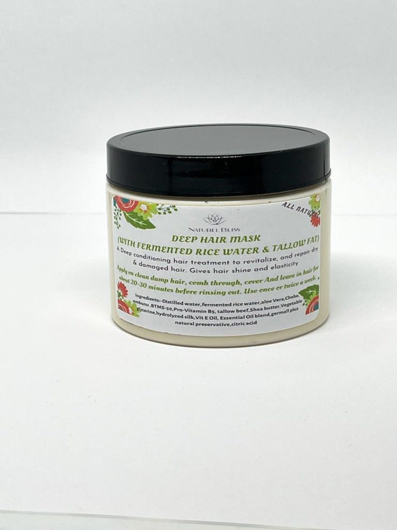 May include: A white jar with a black lid labeled "Deep Hair Mask (With Fermented Rice Water & Tallow Fat)". The label also includes the text "All Natural" and lists the ingredients.