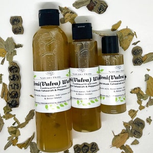 May include: Three amber glass bottles with black caps and labels that read "Joni (Vulva) Wash", "Yoni (Vulva) Wash", and "Yoni (Vulva) Wash". The bottles are on a white surface with dried leaves scattered around them.