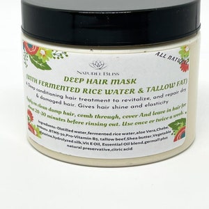 May include: A white jar with a black lid labeled "Deep Hair Mask with Fermented Rice Water & Tallow Fat". The jar is filled with a light beige cream and has a floral design on the front. The label also includes the text "Naturel Bliss" and "All Natural".