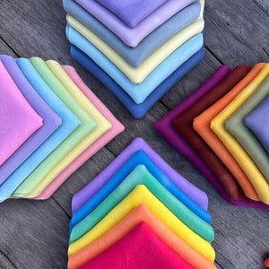 May include: A stack of colorful fabric squares arranged in a rainbow pattern. The squares are made of a soft, fuzzy material and are perfect for crafting projects.
